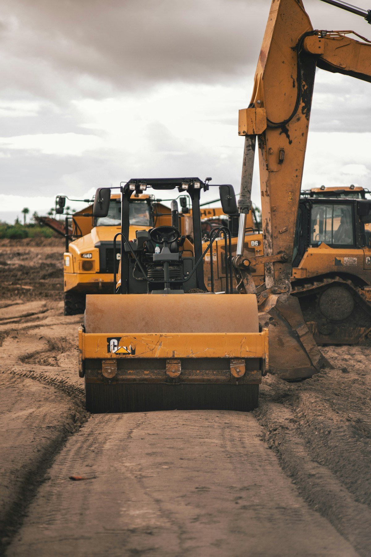 Yellow road roller and excavator on a site