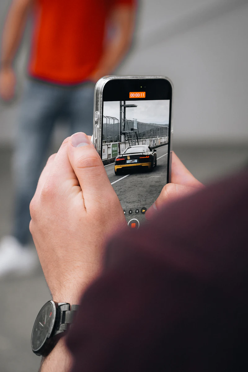 Une main filme une voiture de sport avec un smartphone