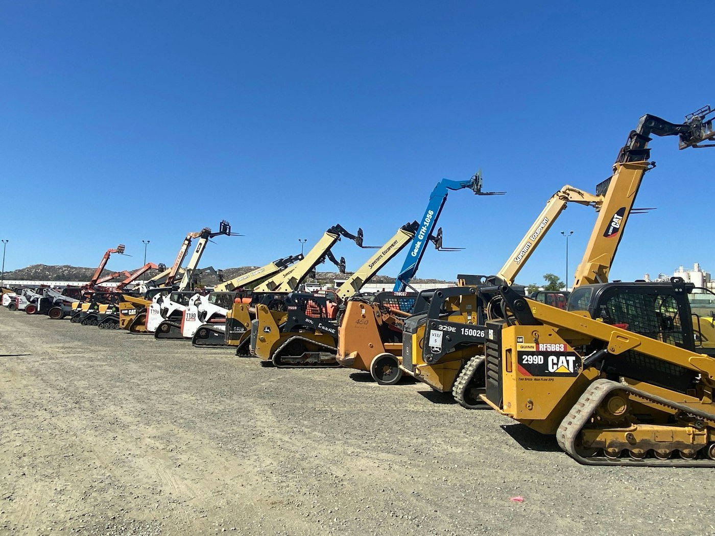 A row of new construction machines at an equipment yard